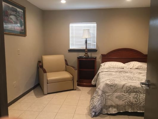 Private bedroom with a bed, chair, and nightstand