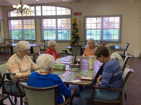 Seniors playing bingo at a table in a community room
