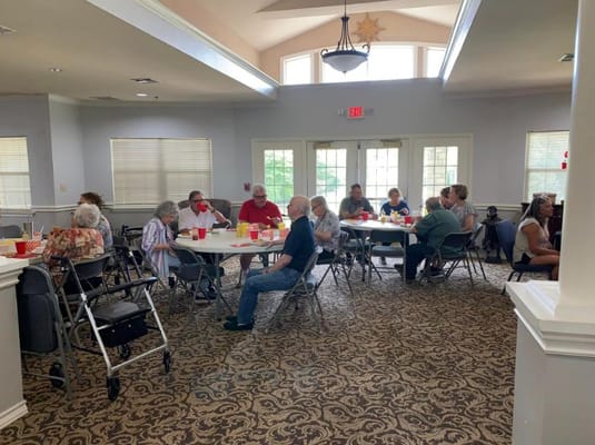 Seniors gathered around tables having a meal in a dining area