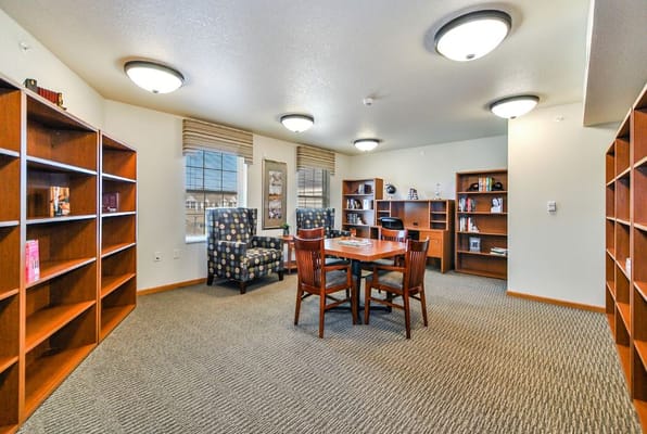 A cozy library space with bookshelves, seating, and a reading table