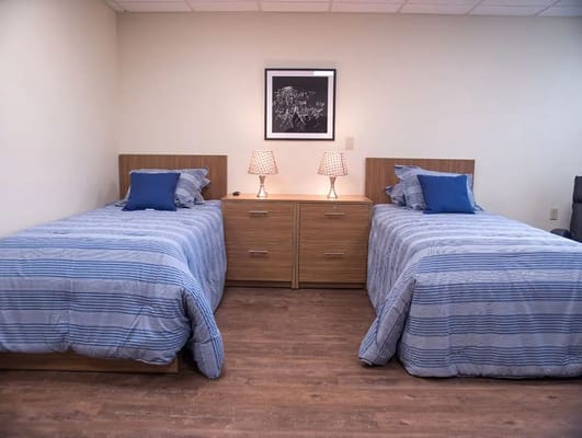 A bedroom with two twin beds, blue striped bedding, and bedside lamps.