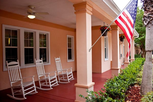 White rocking chairs on a porch with an American flag