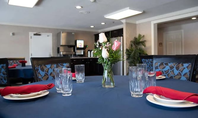 Table set with blue tablecloth, plates, glasses, and a floral centerpiece