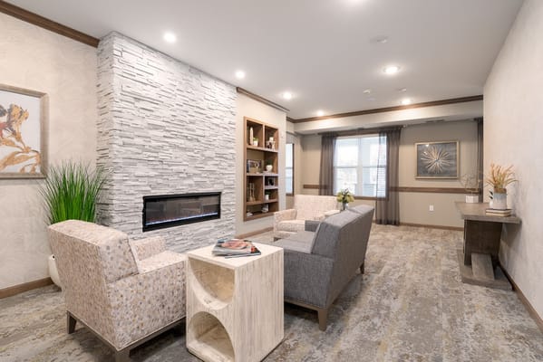 Cozy lounge with two armchairs, a modern coffee table, fireplace, and bookshelf.