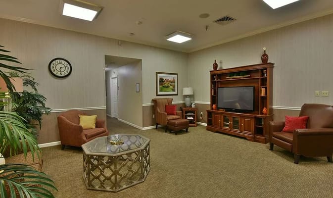 Lounge area with two chairs, a coffee table, and TV