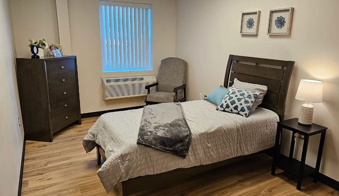 Interior of a private resident room with bed and furniture