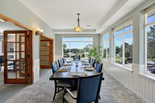 Dining room with a long table and chairs, large windows