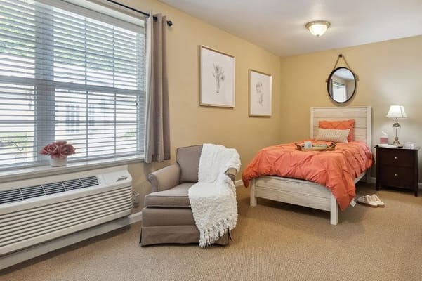 Inviting bedroom with orange bedding and a comfortable chair.