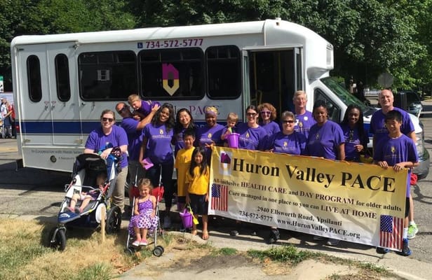 Staff and residents posing next to facility transport bus