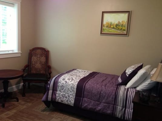 Cozy bedroom with a purple thematic quilt and artwork