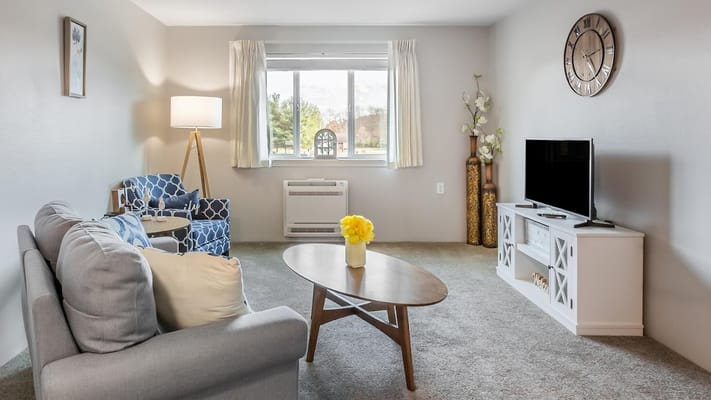 Bright and inviting living room with a sofa, armchairs, and TV.