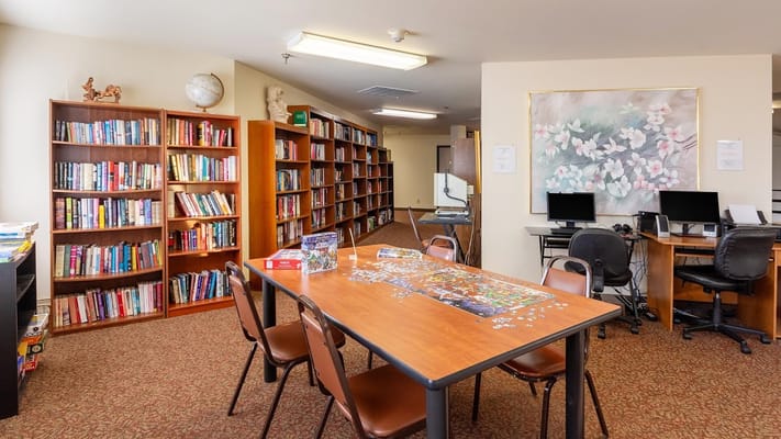 A cozy library and activity room with bookshelves and a puzzle on a table