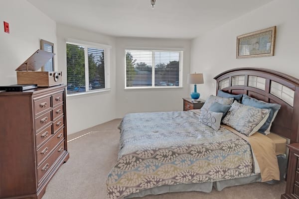 Cozy bedroom with a double bed and natural light from large windows.