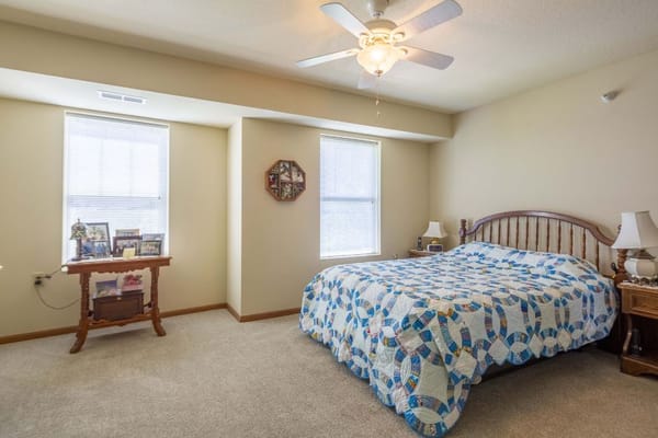 A well-decorated bedroom with a quilted bedspread and ample natural light.