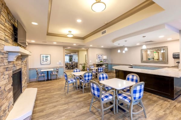 Bright common area with checkered seating and a stone fireplace