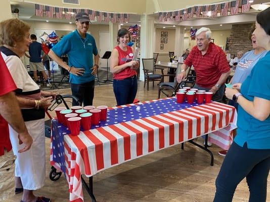 Residents and staff playing a game in a festive common area