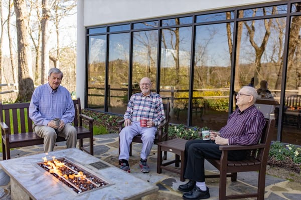 Three senior men relaxing by a fire pit at Kirkwood By the River.