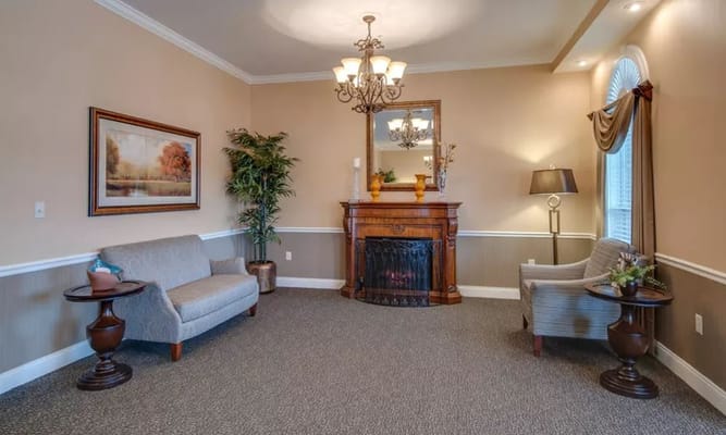 A cozy living room featuring a fireplace, two armchairs, and a sofa.