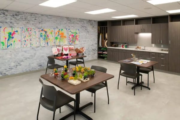 Art room with tables, plants, and colorful paintings on the wall