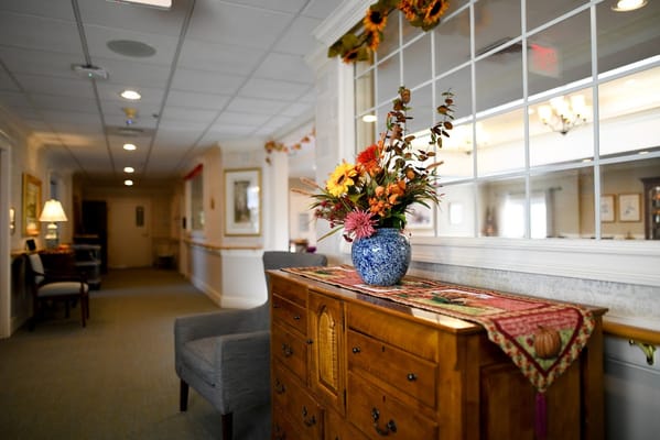 A hallway with a floral arrangement on a wooden sideboard