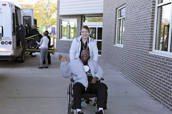 A caregiver assisting a resident in a wheelchair outside