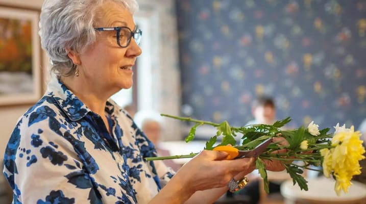 Resident enjoying a flower arranging activity indoors