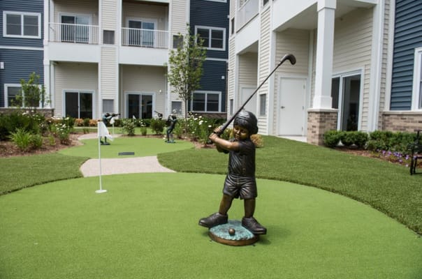 Outdoor putting green with decorative statue and landscaping
