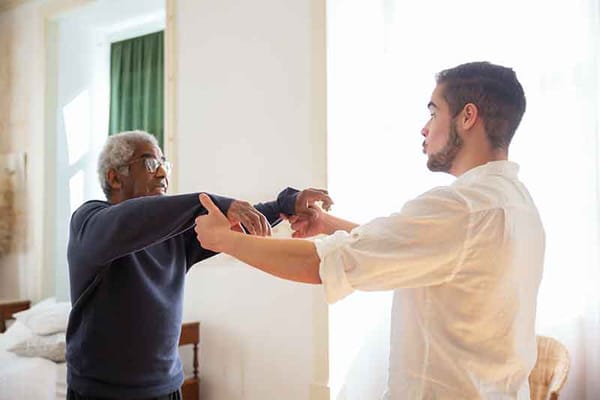 A caregiver assisting a senior man in a therapy session.