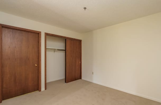 Empty bedroom with closets and beige carpet