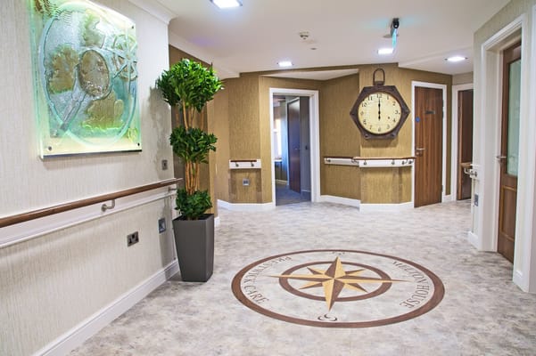 A spacious hallway featuring a compass design on the floor and a wall clock.