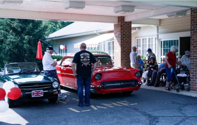 Residents enjoying classic cars at the facility entrance
