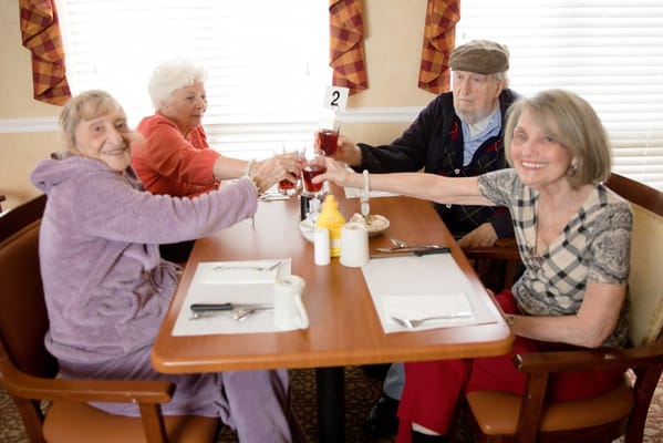 Residents toasting with drinks in a dining room