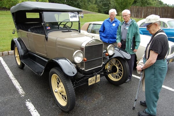 Residents admiring a vintage car in a parking lot