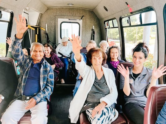 Residents and staff waving inside a facility transport van