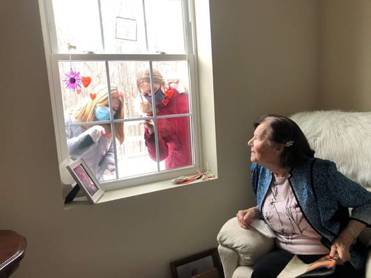 A resident watching visitors through a window