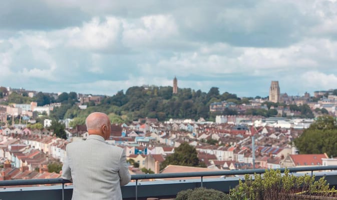 An elderly man overlooking a scenic view of the city.