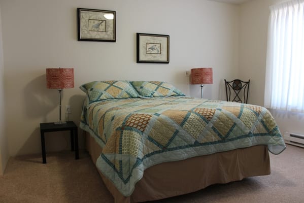 A well-furnished bedroom with a quilted bedspread and side lamps.