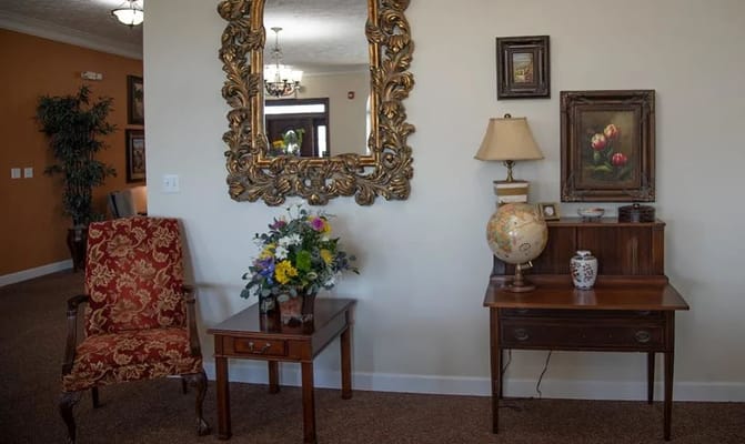 Decorative lobby area featuring a mirror, floral arrangement, and vintage furniture.