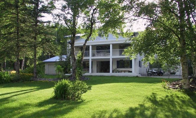Front view of Northern Comfort Assisted Living facility surrounded by lush greenery.