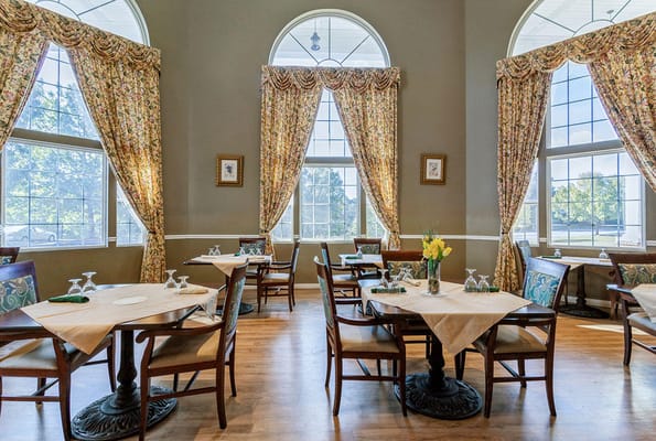 Dining area with tables set for meals and floral curtains