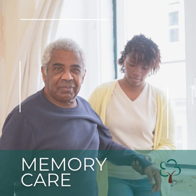 An older man receiving support from a caregiver in a memory care setting.