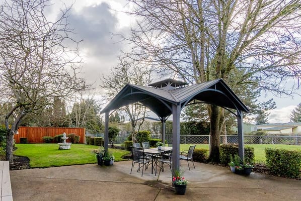 Outdoor gazebo area with seating and greenery