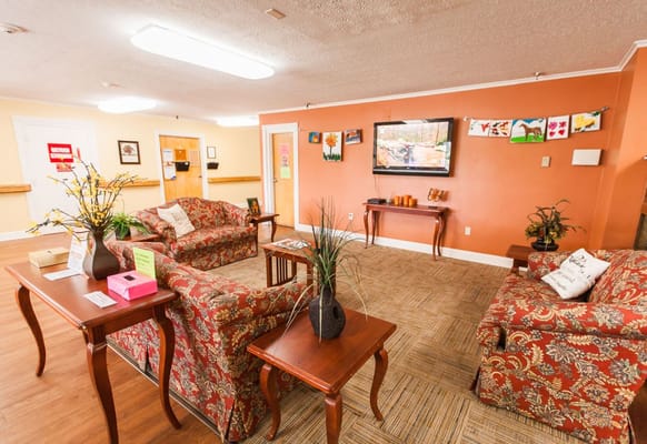Comfortable seating area with floral couches and a television in the background.