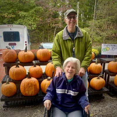 Two residents at a pumpkin patch with pumpkins in the background