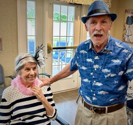 Two residents enjoying a social event, one wearing a hat and pink boa