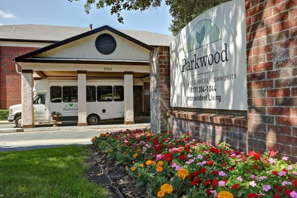 Exterior view of Parkwood Independent Living with flowers and shuttle bus