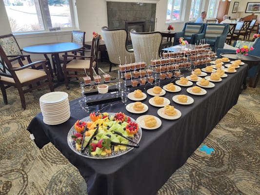 A dessert table featuring cupcakes, fruit platter, and chocolate desserts.