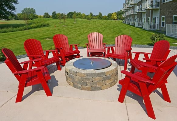 Outdoor seating area with red chairs around a fire pit