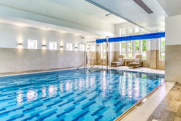 Indoor swimming pool with seating area and large windows