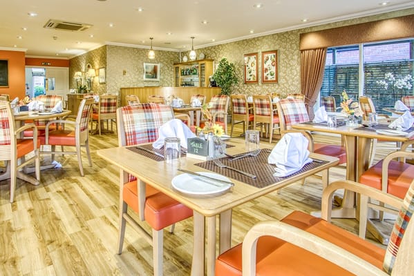 Bright dining area with tables set for a meal, featuring checkered seats.